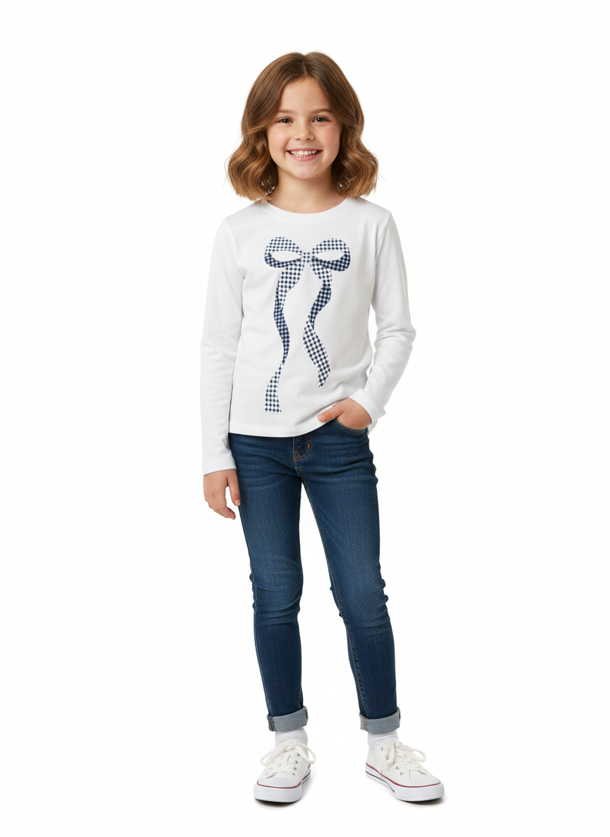 Young girl wearing a white sweater with a blue bow design and blue jeans on a white background