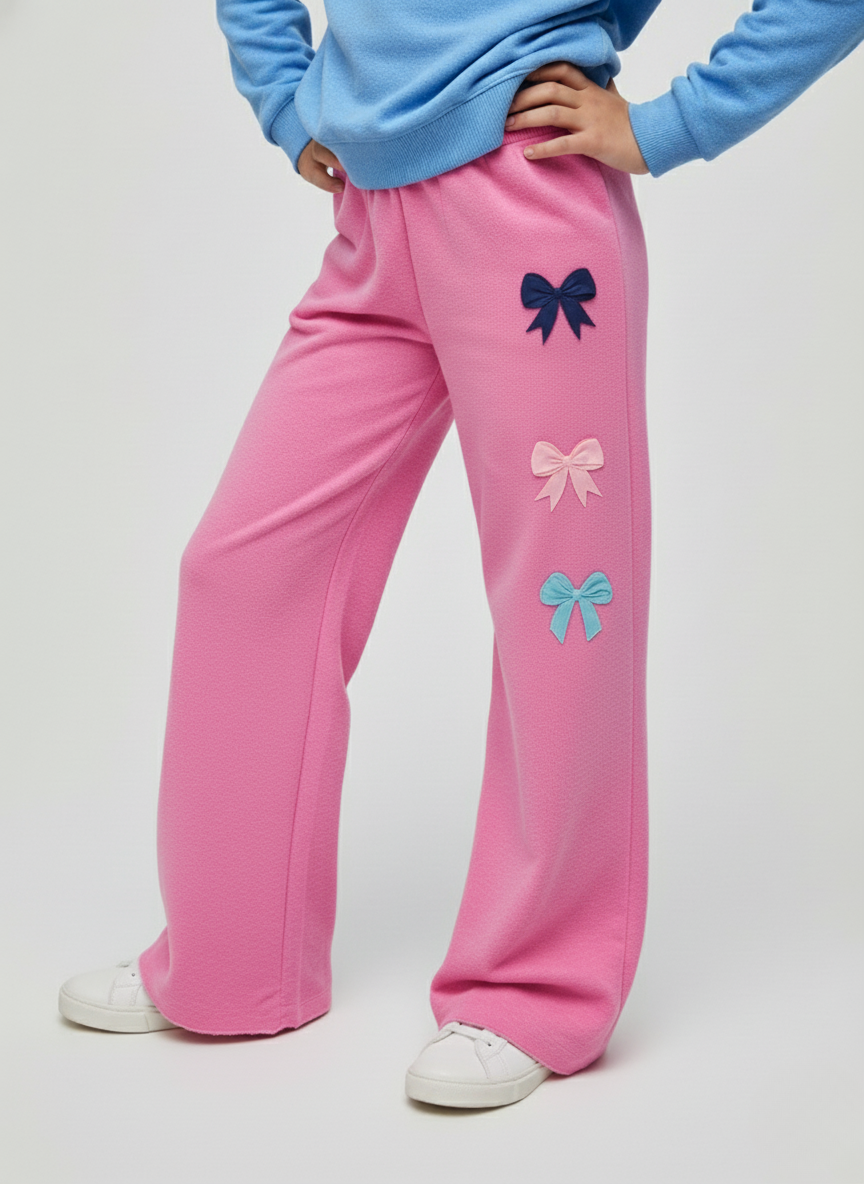 Pink sweatpants with bow designs worn by a person on a white background