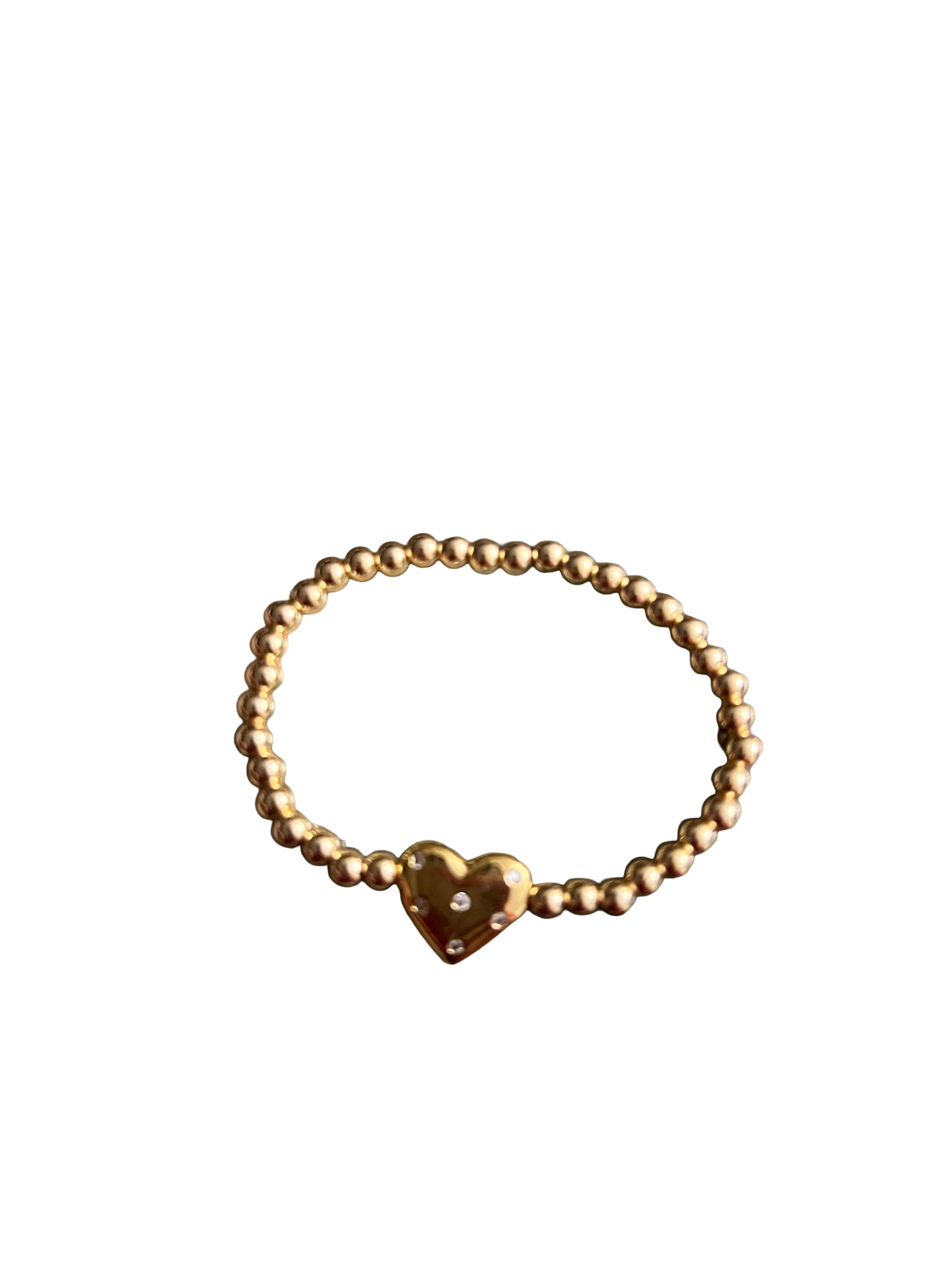 Gold beaded bracelet with a heart charm on a white background